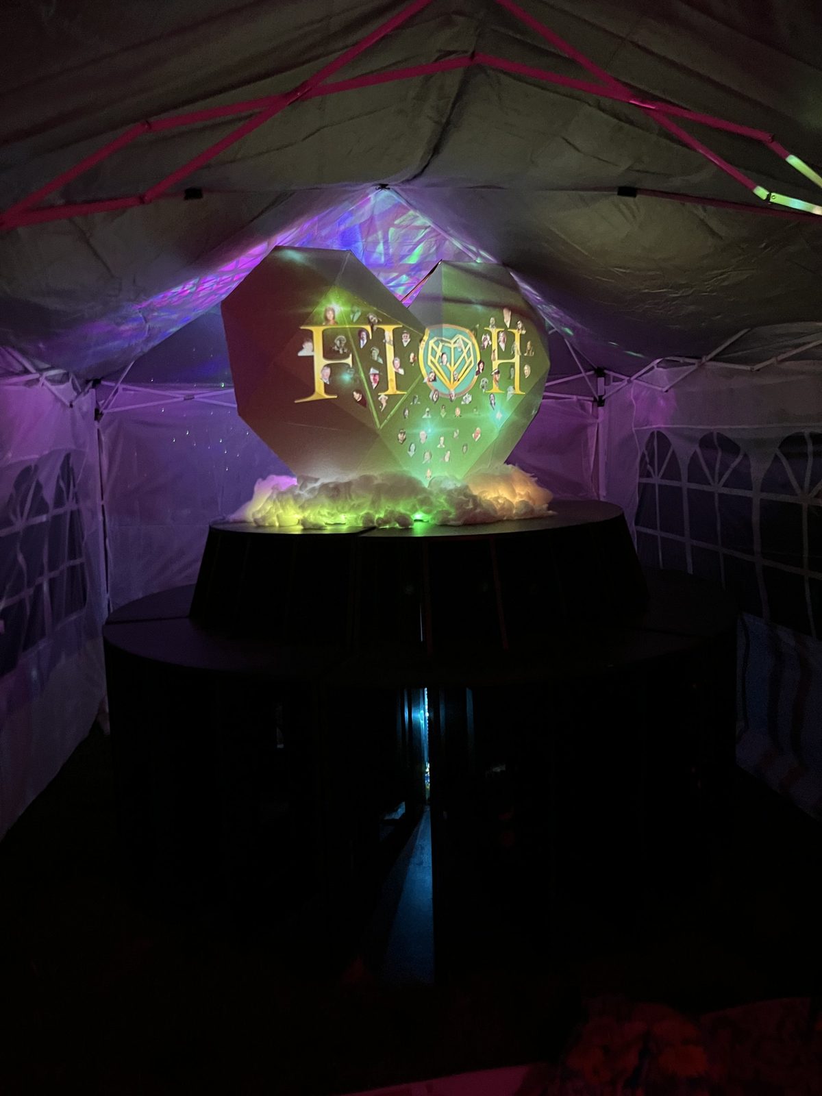 FIOH installed inside a tent at SNRG Festival, portraits and the FIOH logo projected on the heart
